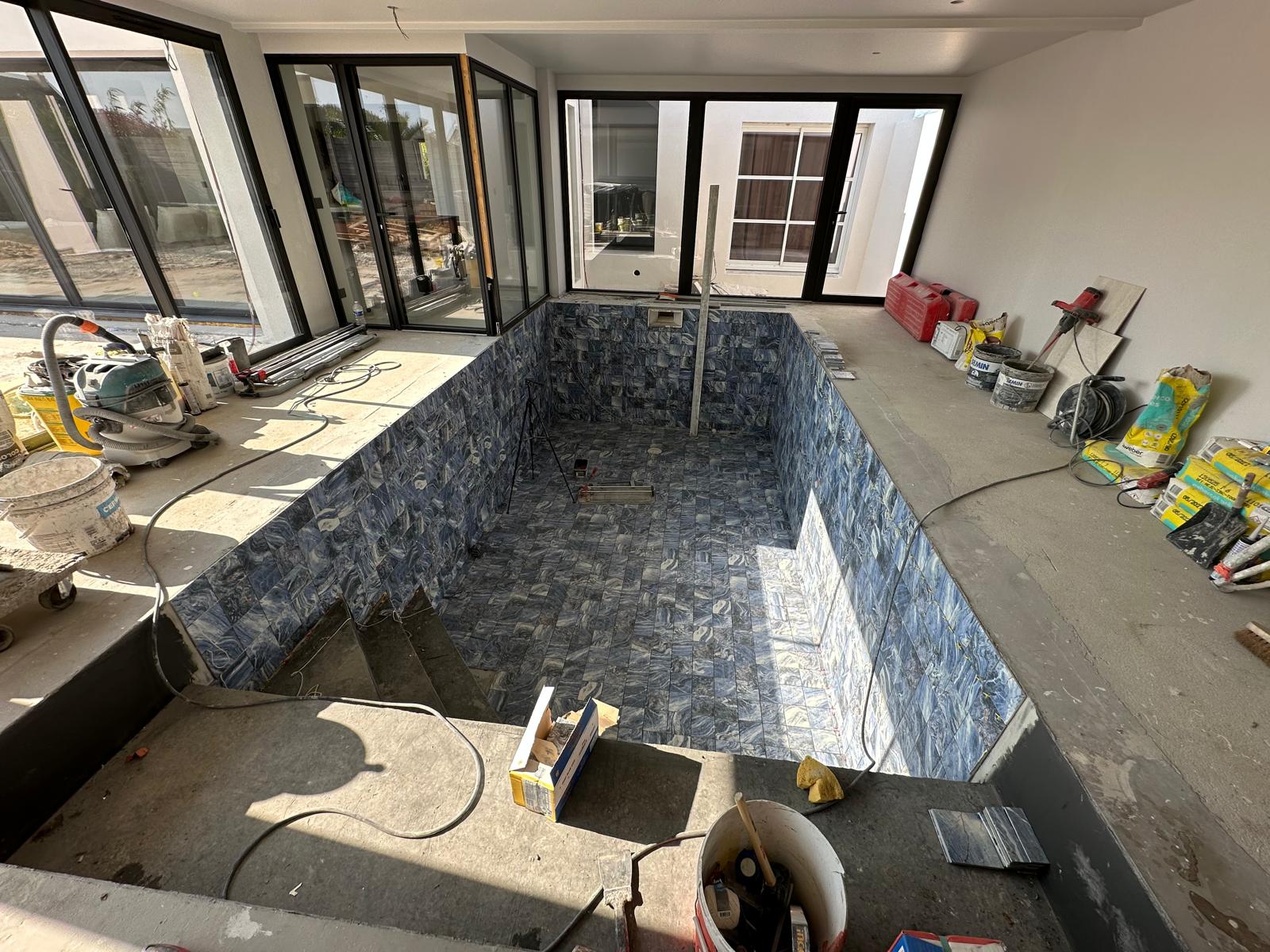 Pose du carrelage d'une piscine intérieure en chantier